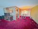 Open-plan living room with dividing wall, decorative furnishings, red carpeting, and vintage chandelier at 7345 E Hinsdale Pl, Centennial, CO 80112