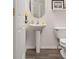 Powder room with pedestal sink, oval mirror, and dark wood-look floors and baseboards at 9604 Brentwood Way # B, Broomfield, CO 80021