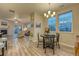 The dining area has hardwood floors, a modern chandelier, a round table, large windows, and is open to the living room at 24806 E Calhoun Pl # A, Aurora, CO 80016