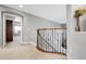 Bright hallway featuring carpet floors, wood and iron banister, and an open doorway to an adjacent bedroom at 3266 Coyote Hills Way, Castle Rock, CO 80109