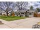 Inviting single-story home with a lush lawn, mature tree, and driveway, perfect for relaxed suburban living at 4825 S Delaware St, Englewood, CO 80110