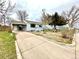Quaint home featuring a carport, light blue paint, a concrete driveway, and mature landscaping at 7901 Newport St, Commerce City, CO 80022