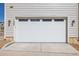 Clean garage door with a concrete driveway and nice rock details at 11400 W Grand Ave, Littleton, CO 80127
