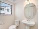 Powder room features a pedestal sink, round mirror, and toilet at 2066 S Holly St # 3, Denver, CO 80222