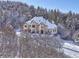 Snow-covered home with a large yard, nestled in a wooded area at 1043 Meteor Pl, Castle Rock, CO 80108