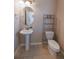 Compact half bathroom featuring a pedestal sink, oval mirror, toilet, and neutral tile flooring at 3565 E 141St Dr, Thornton, CO 80602