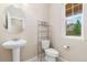 Cozy powder room featuring pedestal sink, toilet, and a window for natural light at 3565 E 141St Dr, Thornton, CO 80602