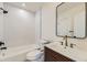 Modern bathroom features sleek white tiling, wood vanity, and black framed mirror at 3201 Albion St, Denver, CO 80207