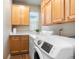 Bright laundry room with wood cabinets, white washer and dryer, and a window at 16456 Wagon Pl, Parker, CO 80134