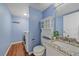 Cozy bathroom featuring blue walls, wooden floors, and a vanity sink with granite countertops at 3528 Morning Glory Dr, Castle Rock, CO 80109