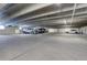 Spacious parking garage with multiple cars parked under a concrete ceiling with hanging lights at 7201 E Quincy Ave # 103, Denver, CO 80237
