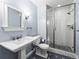 Well-lit bathroom features tiled floors, a pedestal sink, and a tiled shower with a glass door at 7899 E 28Th Pl, Denver, CO 80238