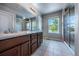 Bright bathroom features a double sink vanity, large mirror, tiled floors, and a walk-in shower with a glass door at 1873 Trevor Cir, Longmont, CO 80501