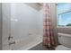 Bright bathroom with a white tiled bathtub and shower, a colorful shower curtain, and a window for natural light at 1873 Trevor Cir, Longmont, CO 80501