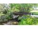 A rustic footbridge stretches over a calm creek, surrounded by lush greenery and natural vegetation at 1873 Trevor Cir, Longmont, CO 80501
