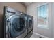 Modern laundry room with front-loading washer and dryer, featuring energy-efficient appliances and a window at 1873 Trevor Cir, Longmont, CO 80501