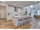 Well-lit kitchen featuring white cabinets, an island with seating, and a stylish backsplash, with view to stairwell at 11246 Bellsong Ln, Littleton, CO 80125