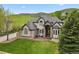 Well-maintained two-story home with stone and light tan siding, a manicured lawn, and mountain views at 10 Summit Ash, Littleton, CO 80127
