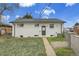 Rear exterior of a white brick home with a green door, lawn, and chain-link fence at 7001 Alan Dr, Denver, CO 80221