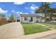 Quaint single-story home with a driveway leading to a detached garage and a vibrant green lawn at 7001 Alan Dr, Denver, CO 80221