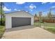 Detached garage with a gray door and concrete driveway under a blue sky. Chain link fence included at 7001 Alan Dr, Denver, CO 80221