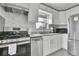 Modern kitchen with stainless steel appliances, white cabinets, and ample counter space and tile flooring at 7001 Alan Dr, Denver, CO 80221