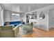 Cozy living room with hardwood floors, a blue couch, green chairs, and an open view of the kitchen at 7001 Alan Dr, Denver, CO 80221