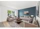 Staged living room with blue accent wall, neutral furniture, hardwood flooring, and large window at 325 Mulberry Cir, Broomfield, CO 80020