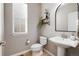 Cozy powder room featuring a pedestal sink, modern mirror, and stylish decorative shelving at 6236 S Millbrook Way, Aurora, CO 80016