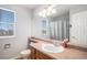 Bright bathroom with a single sink, toilet, large mirror, and natural light from a window at 11499 Kenton St, Commerce City, CO 80640