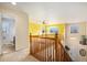 Bright landing with wooden banister, carpet flooring, and access to the bathroom and the upper level of the home at 11499 Kenton St, Commerce City, CO 80640