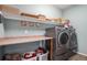 Laundry room with front-loading machines, a folding counter, and overhead storage shelves at 11499 Kenton St, Commerce City, CO 80640