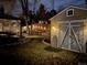 Evening view of backyard featuring a shed, fence with lights, manicured grass, and covered patio at 6045 S Cook St, Centennial, CO 80121