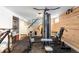 Basement gym area complete with work out machine, exposed wood beams, and stairs to the main floor at 6045 S Cook St, Centennial, CO 80121