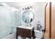 Updated bathroom featuring a modern vanity, round mirror, and glass-enclosed tub and shower at 6045 S Cook St, Centennial, CO 80121