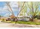 Inviting single-story home with mature trees shading the front yard, gray brick and a wooden accent at 6045 S Cook St, Centennial, CO 80121