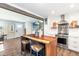 Open kitchen with a rustic island, stainless steel appliances, and views into the adjacent living room at 6045 S Cook St, Centennial, CO 80121