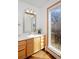 Bright bathroom featuring a wood vanity, white countertop, and large window with a view of trees at 1340 Deerpath Trl, Franktown, CO 80116