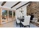 Open dining room featuring a stone fireplace, wooden beams, and outdoor views at 1340 Deerpath Trl, Franktown, CO 80116