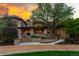Stately stone home with meticulous landscaping, a winding driveway, and a sunset sky at 45 Charlou Cir, Cherry Hills Village, CO 80111