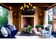 Outdoor seating area with fireplace and chandelier, with view of trees and lush landscaping at 45 Charlou Cir, Cherry Hills Village, CO 80111