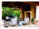 Outdoor seating area with fireplace and chandelier, with view of trees and lush landscaping at 45 Charlou Cir, Cherry Hills Village, CO 80111
