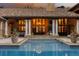 Outdoor pool with stone patio, view of house with pillars, doors, and window lit up from the inside at 45 Charlou Cir, Cherry Hills Village, CO 80111