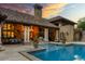 Outdoor pool with stone patio, covered veranda with dining set and grill, all under a stunning sunset sky at 45 Charlou Cir, Cherry Hills Village, CO 80111