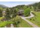 Breathtaking aerial view of the home surrounded by lush greenery, pond and a winding road at 4230 S Meadow Brook Ln, Evergreen, CO 80439