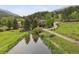 Picturesque home surrounded by a pond and lush greenery with mountain views at 4230 S Meadow Brook Ln, Evergreen, CO 80439
