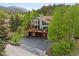 Stunning view of a multi-level home with decks, a driveway, mature trees, and mountain scenery at 4230 S Meadow Brook Ln, Evergreen, CO 80439