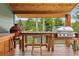 Covered outdoor grilling area with various grills and a scenic wooded view at 4230 S Meadow Brook Ln, Evergreen, CO 80439