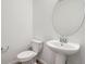 Well-lit powder room with a pedestal sink, toilet, and round mirror for a modern look at 1986 S Haleyville Way, Aurora, CO 80018