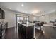 Kitchen with dark wood floors, stainless appliances, granite counters and view into dining and living room at 9608 Albion Ln, Thornton, CO 80229